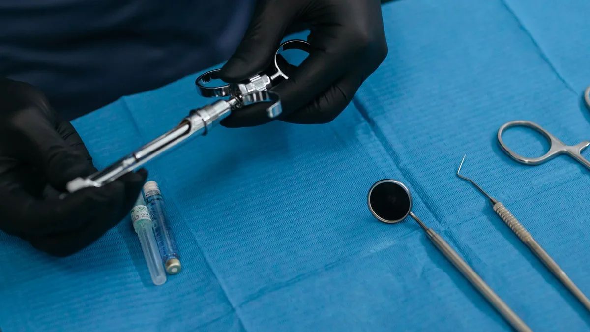 Detailed image showcasing dental equipment, including anesthesia syringe and tools, on blue cloth.