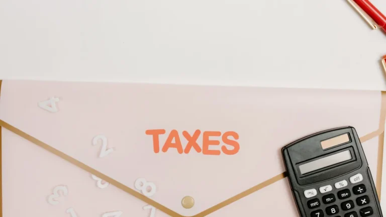 Flat lay of a calculator and folder labeled 'Taxes' for finance and accounting.