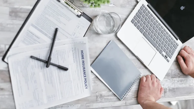 Top view of home insurance forms, laptop, and documents on a desk, conveying a professional office setting.