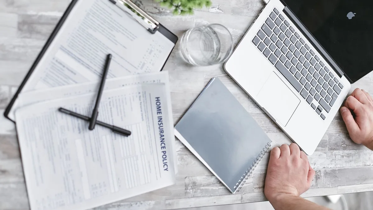 Top view of home insurance forms, laptop, and documents on a desk, conveying a professional office setting.