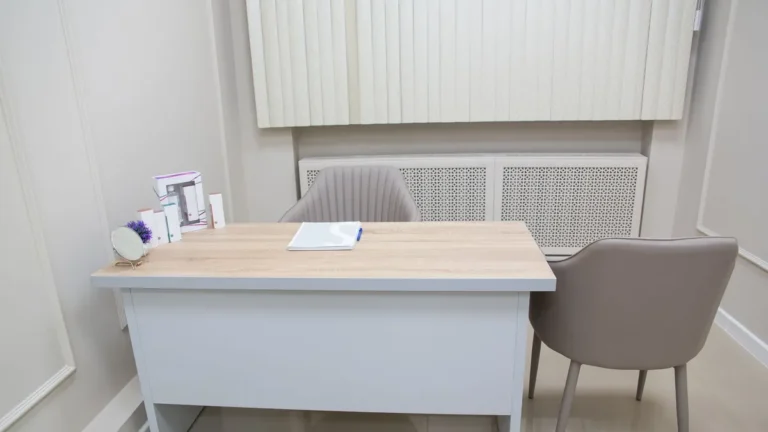 Clean and organized medical office desk with chairs and equipment, perfect for healthcare settings.