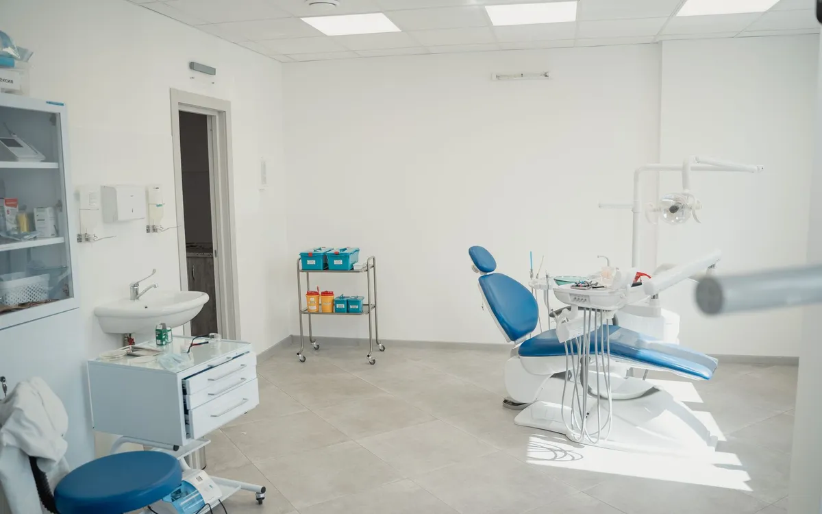 Jasny gabinet stomatologiczny z pustym fotelem, lampą i szafkami przed wizytą