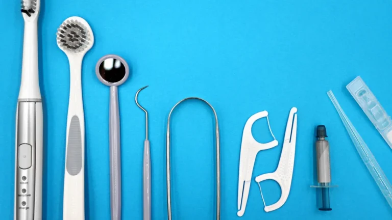 Flat lay of dental care tools including toothbrushes, dental mirror, and floss sticks on blue background.
