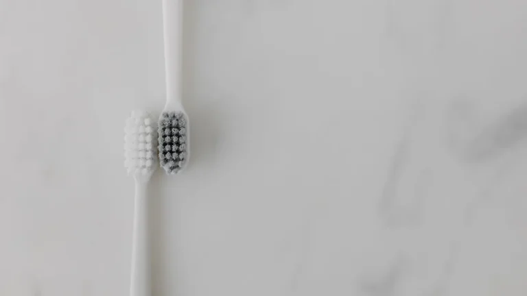 A minimalist image of two toothbrushes with contrasting bristles on a marble background, ideal for dental care themes.