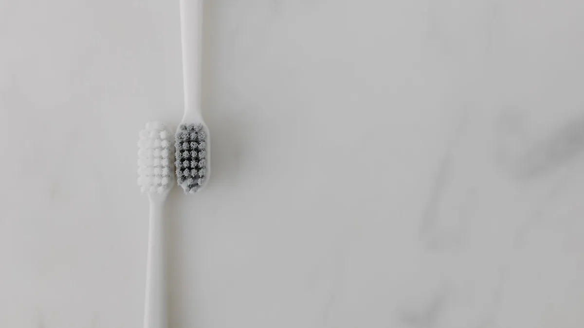 A minimalist image of two toothbrushes with contrasting bristles on a marble background, ideal for dental care themes.