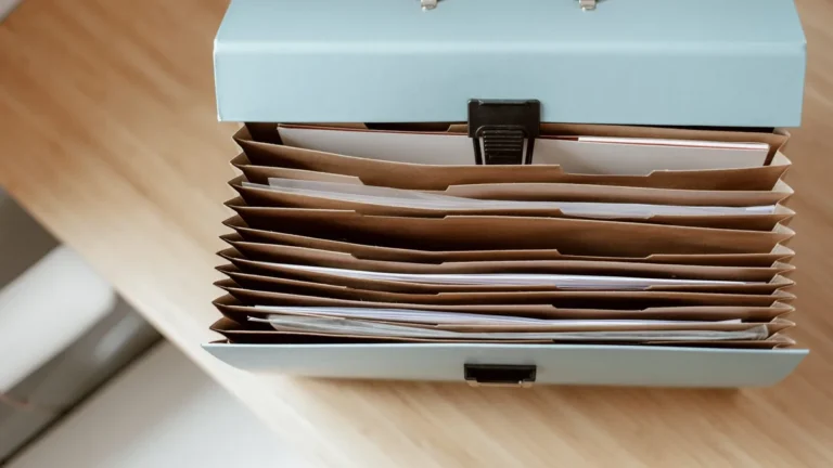 From above of briefcase for documents with papers placed on wooden table in daytime