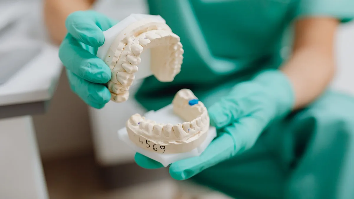 Close-up of a dental cast held with latex gloves in a clinical setting.