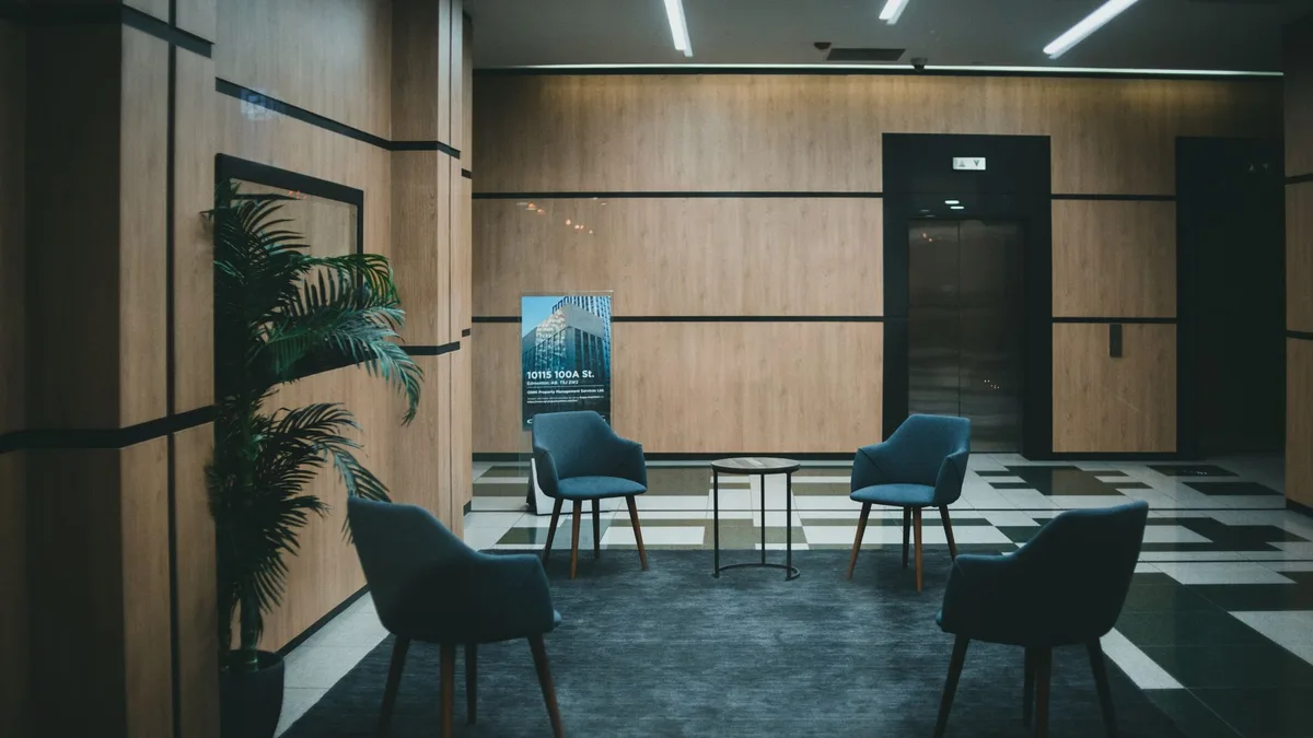 A stylish office lobby featuring chic chairs and a minimalistic design with a neutral tone.