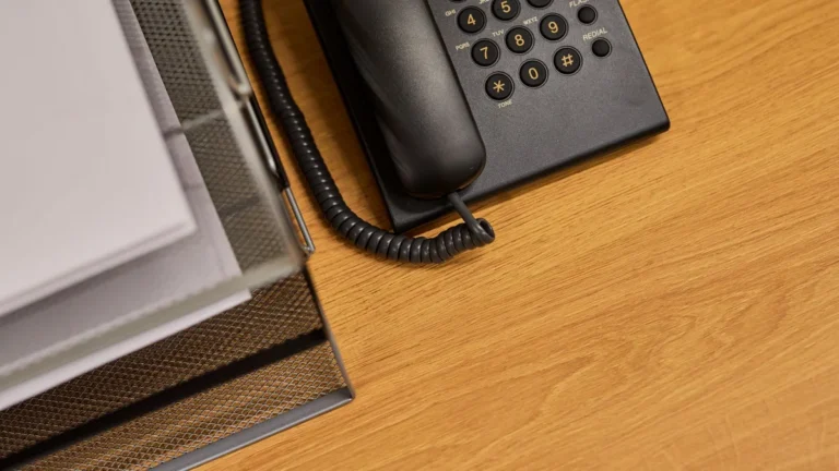 A tidy office desk featuring a classic black telephone and organized documents.