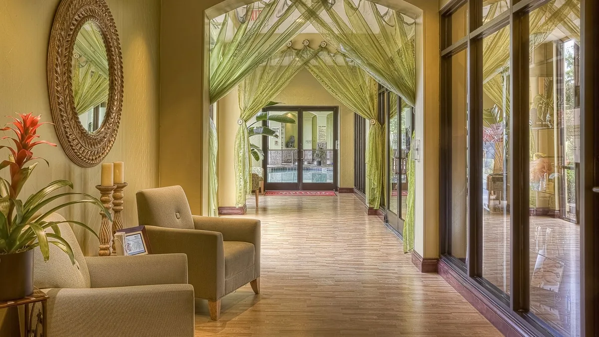 Luxurious hotel hallway featuring elegant green drapes and cozy seating area with warm lighting.