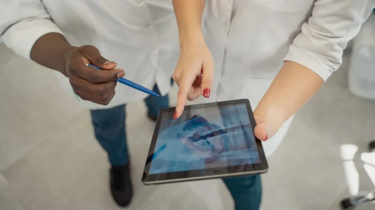 Two medical professionals analyzing a dental x-ray on a tablet. Collaborative healthcare setting.