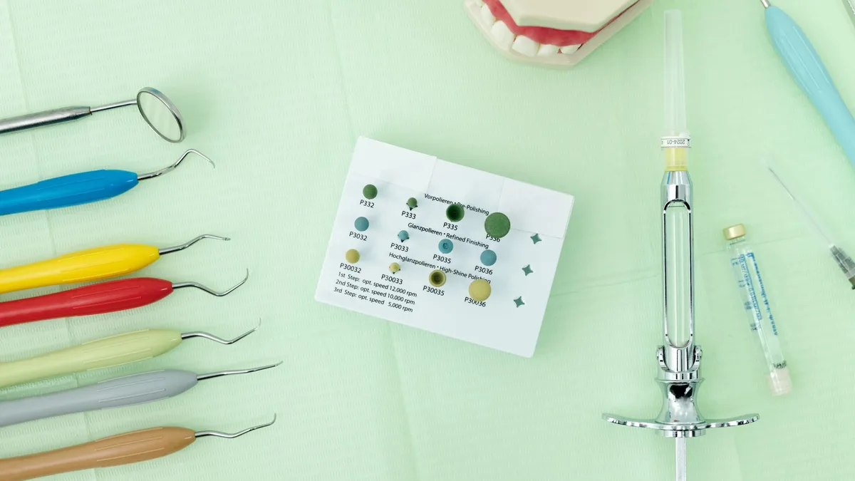 Close-up of colorful dental tools and materials arranged on a green surface for dentistry.