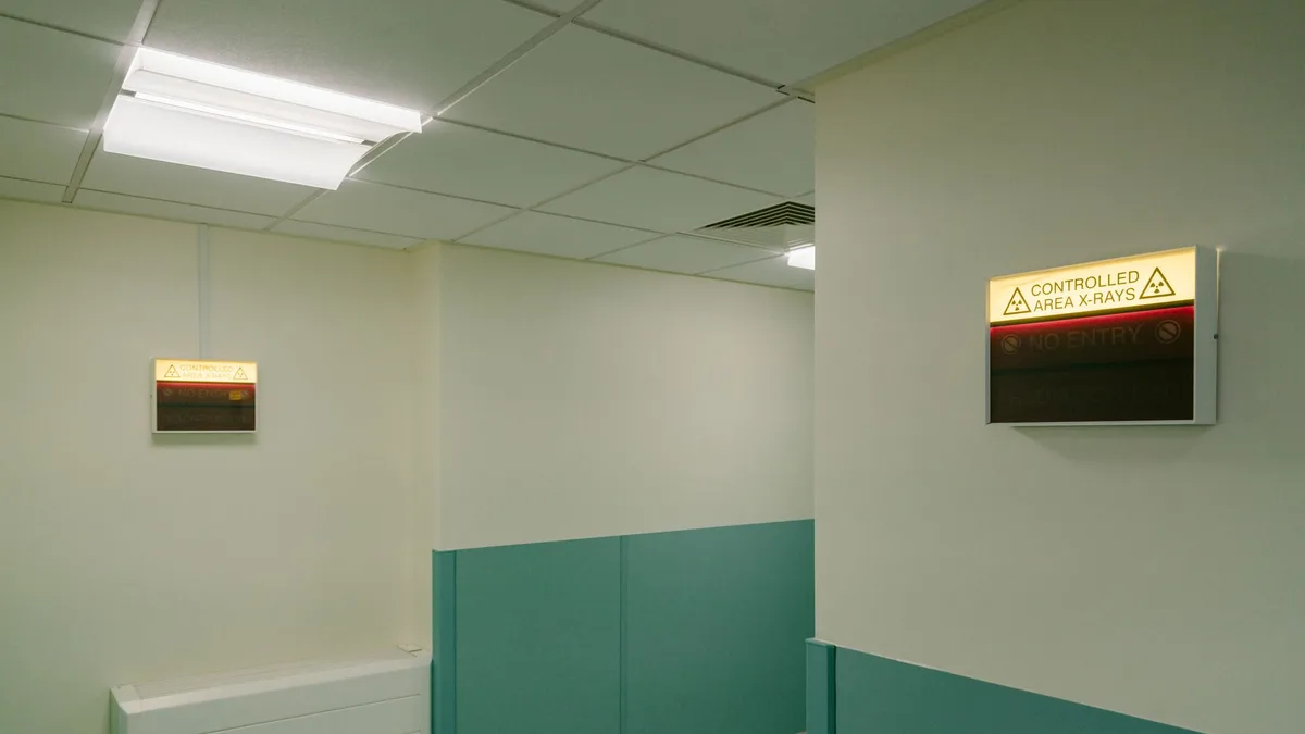 Interior hospital hallway with illuminated X-Ray area warning signs.