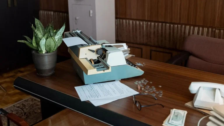 Retro office setting with a vintage typewriter, papers, and coins on a wooden desk.