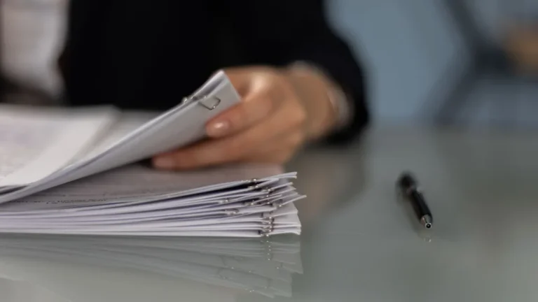 Close-up of a professional organizing a stack of documents on a desk.