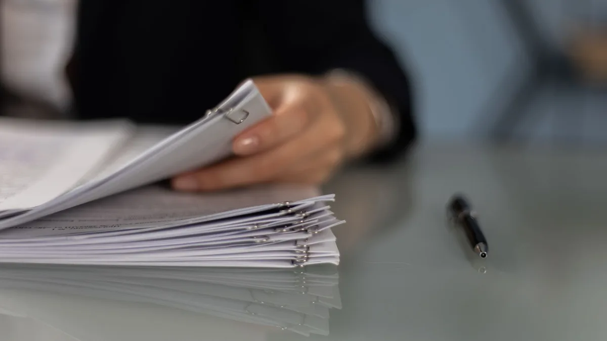 Close-up of a professional organizing a stack of documents on a desk.