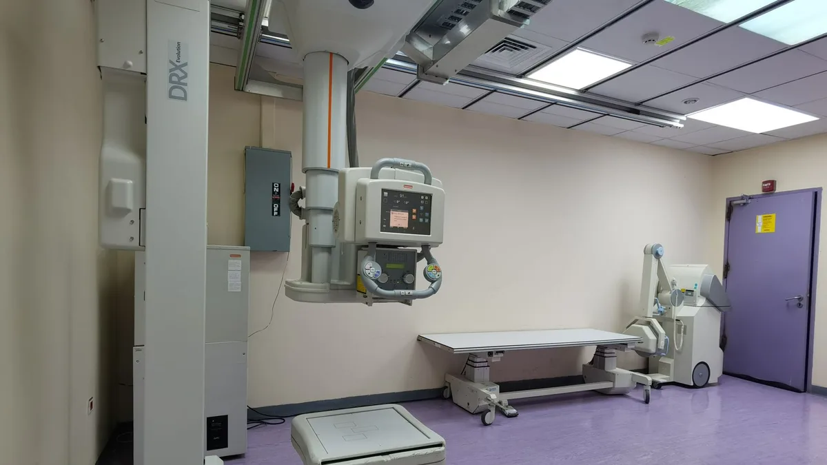 Interior view of a well-equipped hospital X-ray room with medical imaging devices.