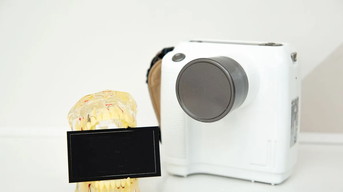 Close-up of a dental model and instant camera on a white surface, showcasing technology and healthcare.