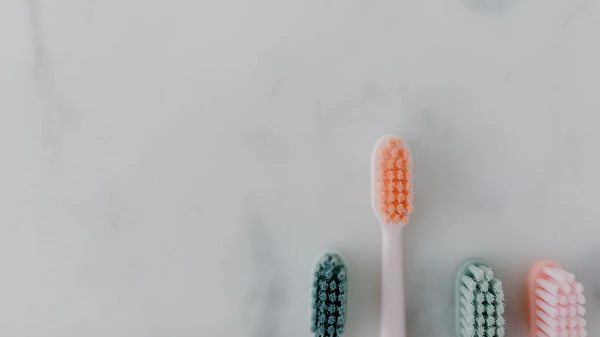 A clean and simple flat lay of four colorful toothbrushes on a marble surface.
