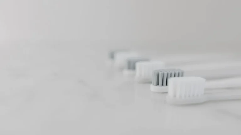 A modern and clean still life composition featuring multiple toothbrushes aligned on a marble surface with copy space.