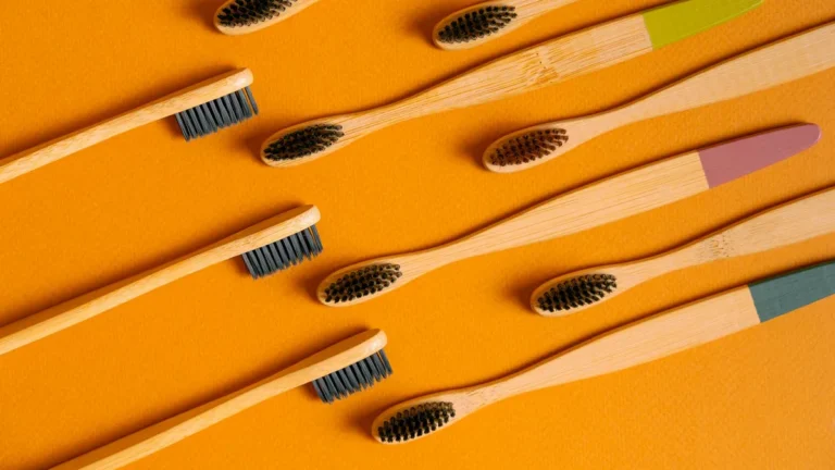 Flatlay of bamboo toothbrushes on vibrant orange, highlighting eco-friendly dental care.