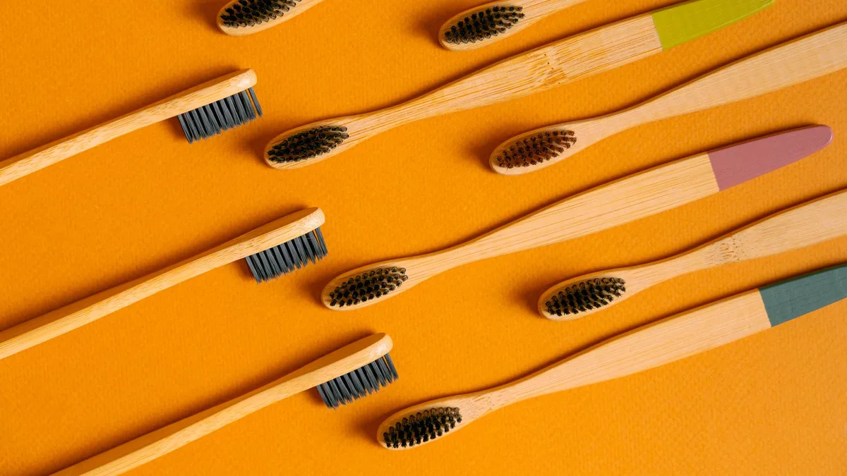 Flatlay of bamboo toothbrushes on vibrant orange, highlighting eco-friendly dental care.