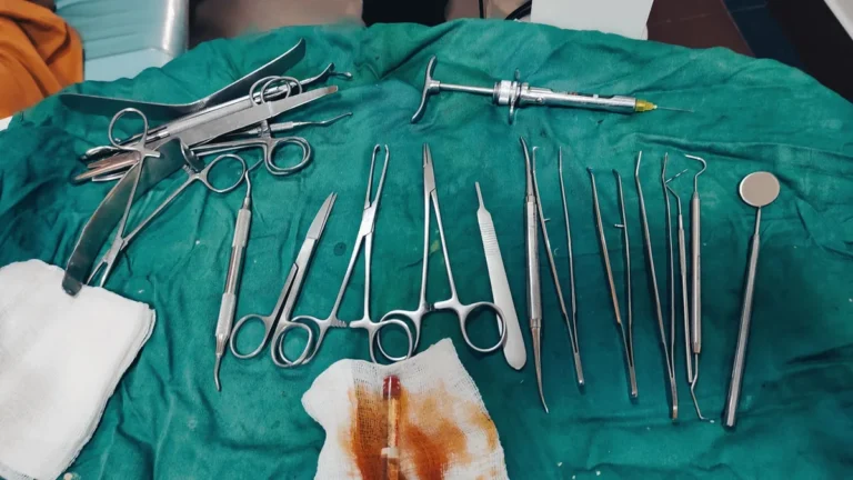 Close-up view of surgical tools arranged on green medical drapes in a clinical setting.
